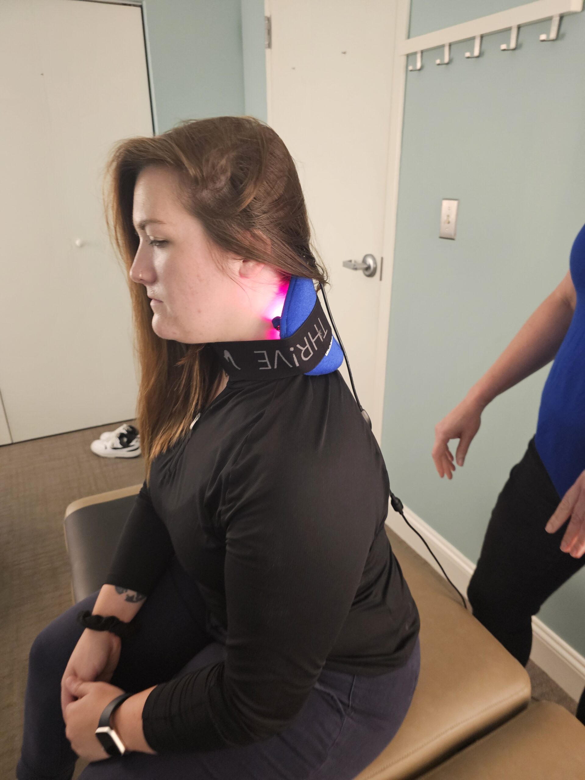 a woman sitting with a laser therapy device on to ease her pain